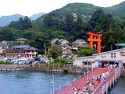 mountainous Moto-Hakone Port along lake Ashi showing tourists lined-up to board the sea pirate ship or kaizokusen with the orange and black torii sign on the background announcing the presence of the Hakone Shrine in the city